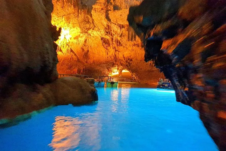 Beleuchtete unterirdische Höhle mit leuchtend blauem Wasser und felsigen Wänden