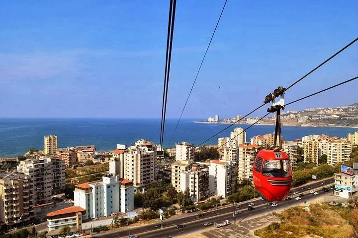 Rote Seilbahn über der Skyline einer Küstenstadt
