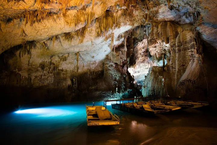 Beleuchtete unterirdische Höhle mit Stalaktiten und kleinen Booten auf dem Wasser